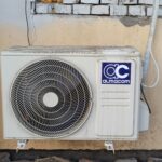 A well-used outdoor air conditioning unit affixed to a brick wall, showcasing urban climate control.